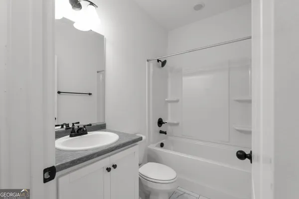 a bathroom with a granite countertop sink a toilet and shower