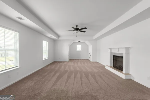 an empty room with windows and fireplace