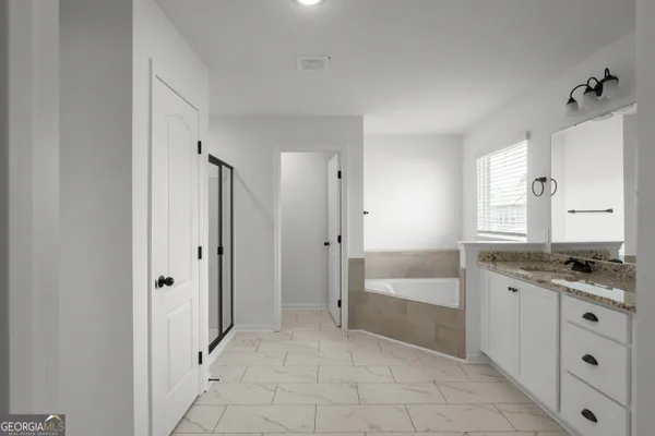 a spacious bathroom with a granite countertop sink a mirror and a bathtub