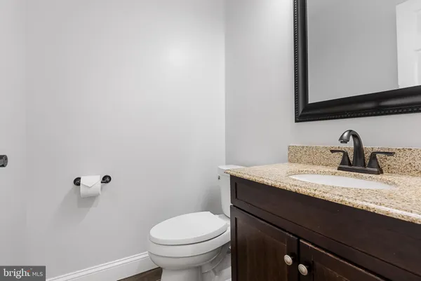 a bathroom with a granite countertop sink and a toilet