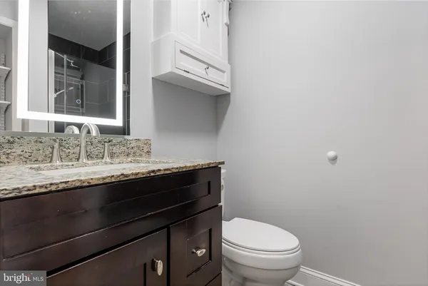 a bathroom with a granite countertop toilet sink and mirror