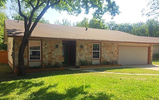 3305 Spaniel Drive Austin, TX 78759 - Photo 3 of 20 A well-maintained facade features a stone veneer, a manicured lawn, and an attached garage.