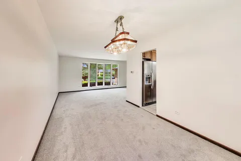 an empty room with a chandelier fan and windows