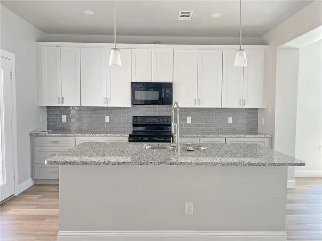 a kitchen with granite countertop a sink a stove and cabinets
