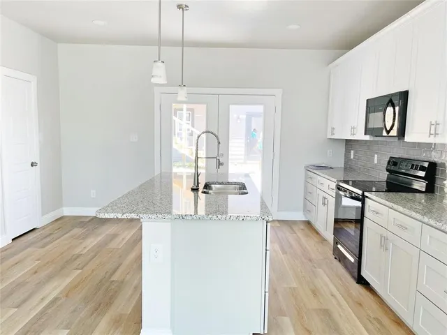 a kitchen with stainless steel appliances granite countertop a stove a sink and a refrigerator