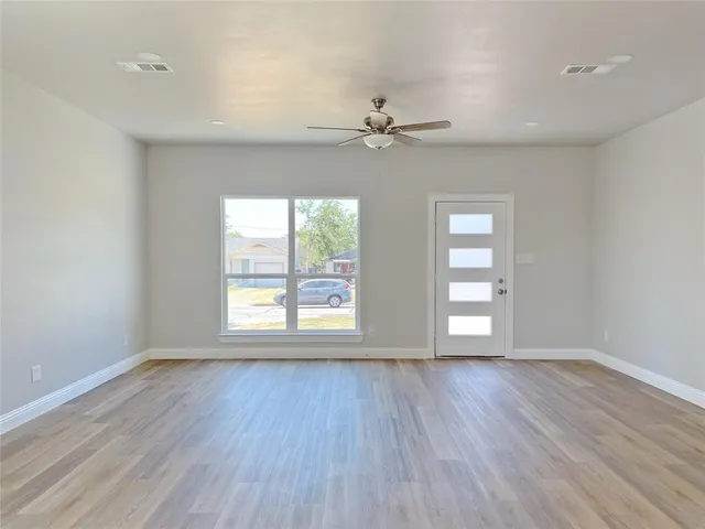 a view of an empty room with wooden floor and a window