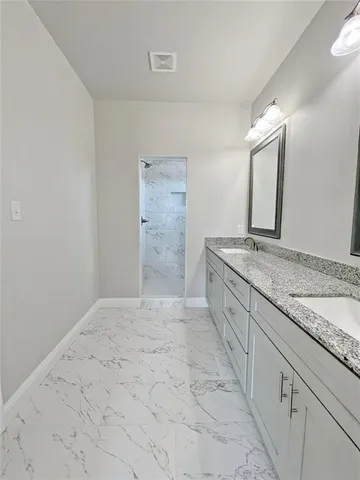 a spacious bathroom with a granite countertop sink and a mirror