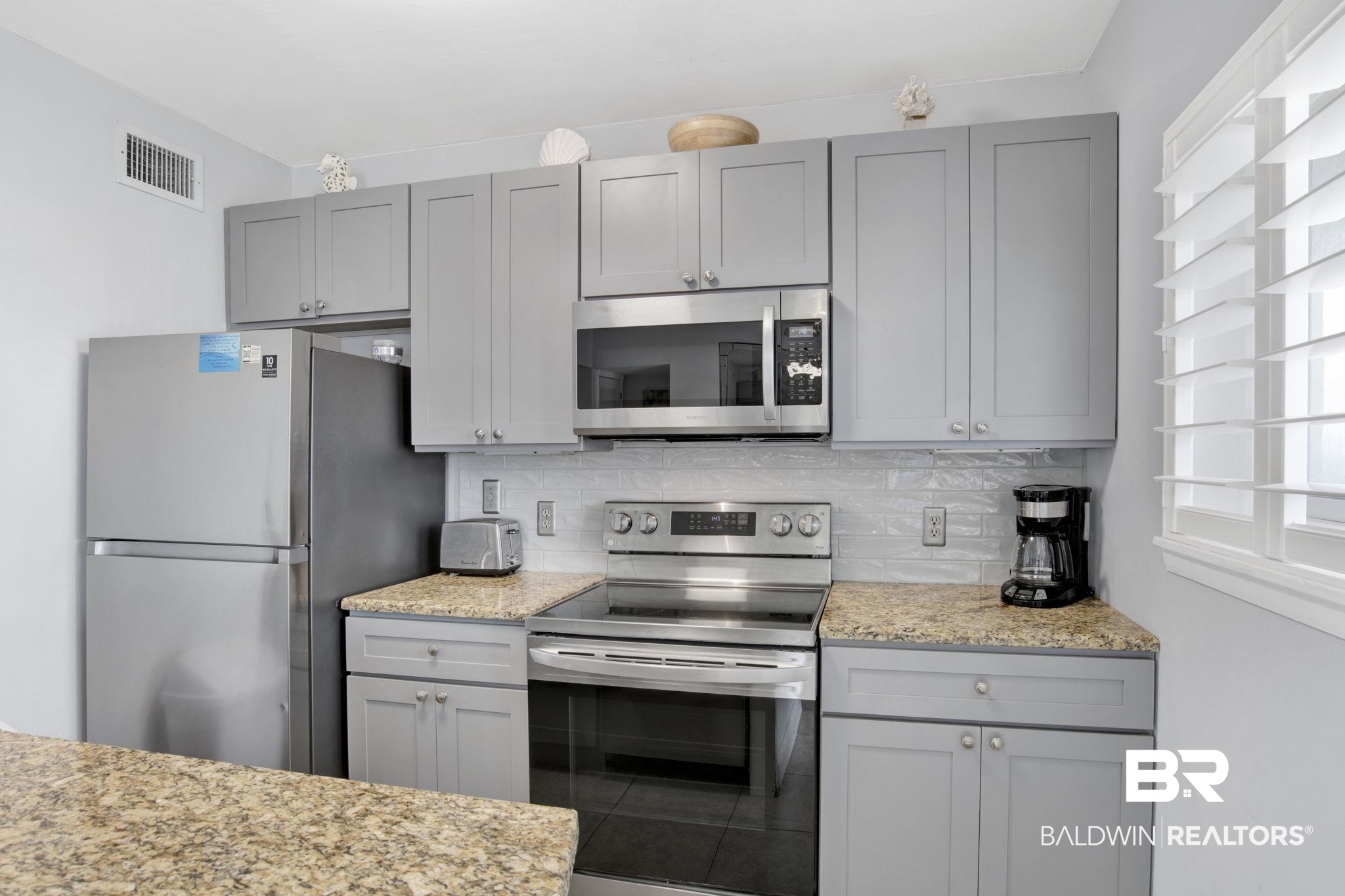 375 Plantation Road, Unit 5514 Gulf Shores, AL 36542 - Photo 15 of 44 Kitchen with appliances with stainless steel finishes, gray cabinets, backsplash, and light stone counters