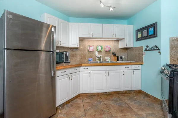 a kitchen with white cabinets and refrigerator