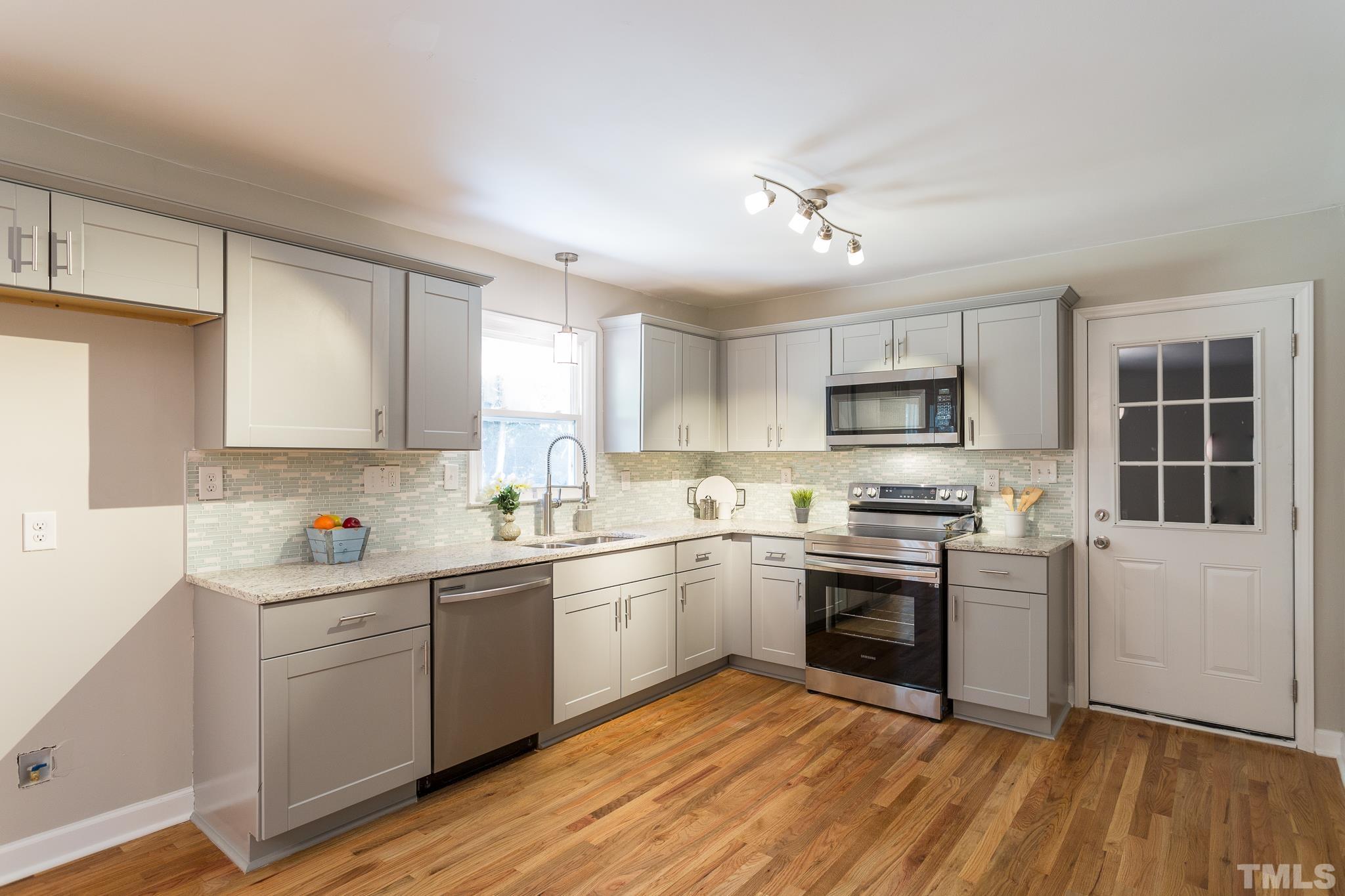 4809 Pearl Road Raleigh, NC 27610 - Photo 10 of 34 a kitchen with stainless steel appliances a sink cabinets and wooden floor