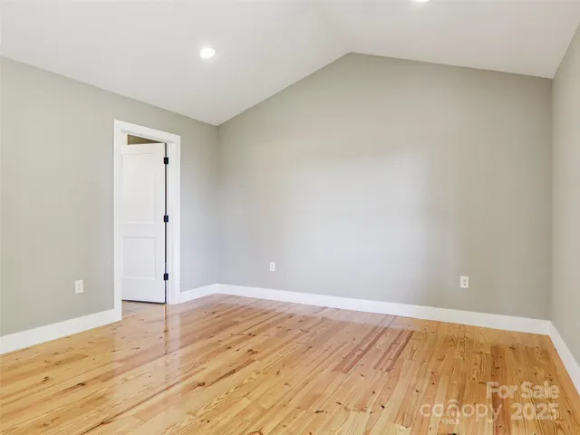 a view of an empty room with wooden floor and window