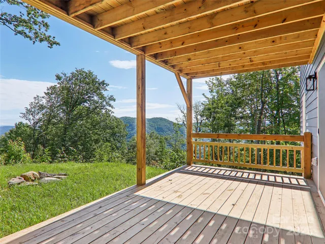 a view of a wooden house with a yard and large trees