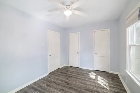 a view of an empty room with window and wooden floor