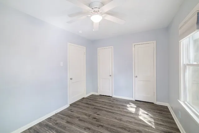 a view of an empty room with window and wooden floor