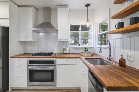 a kitchen with granite countertop a sink stainless steel appliances and cabinets