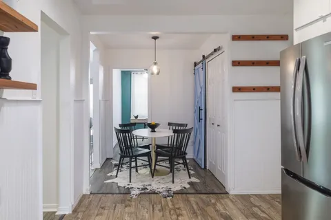 a dining room with wooden floor and stainless steel appliances