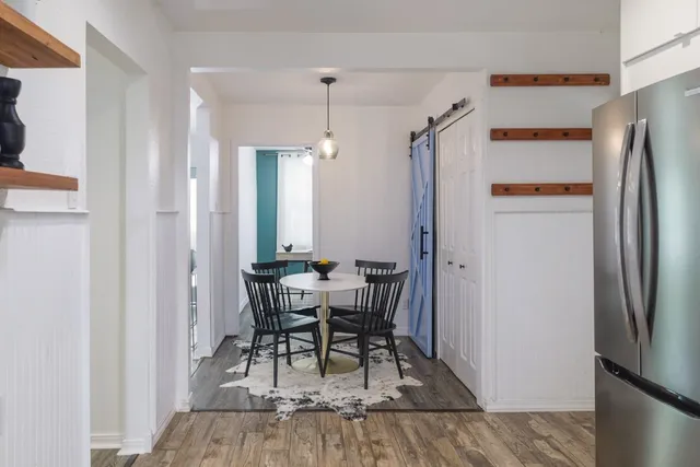 a dining room with wooden floor and stainless steel appliances
