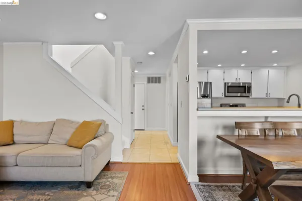 a living room with stainless steel appliances furniture and a wooden floor