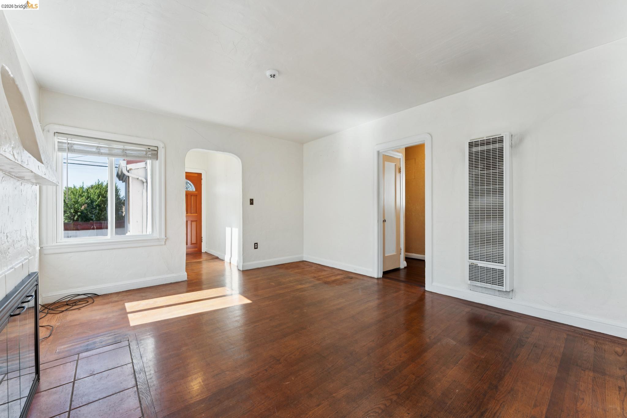 978 43rd Street Oakland, CA 94608 - Photo 11 of 46 Spacious room featuring wood-finish flooring, white walls, and a large window with blinds