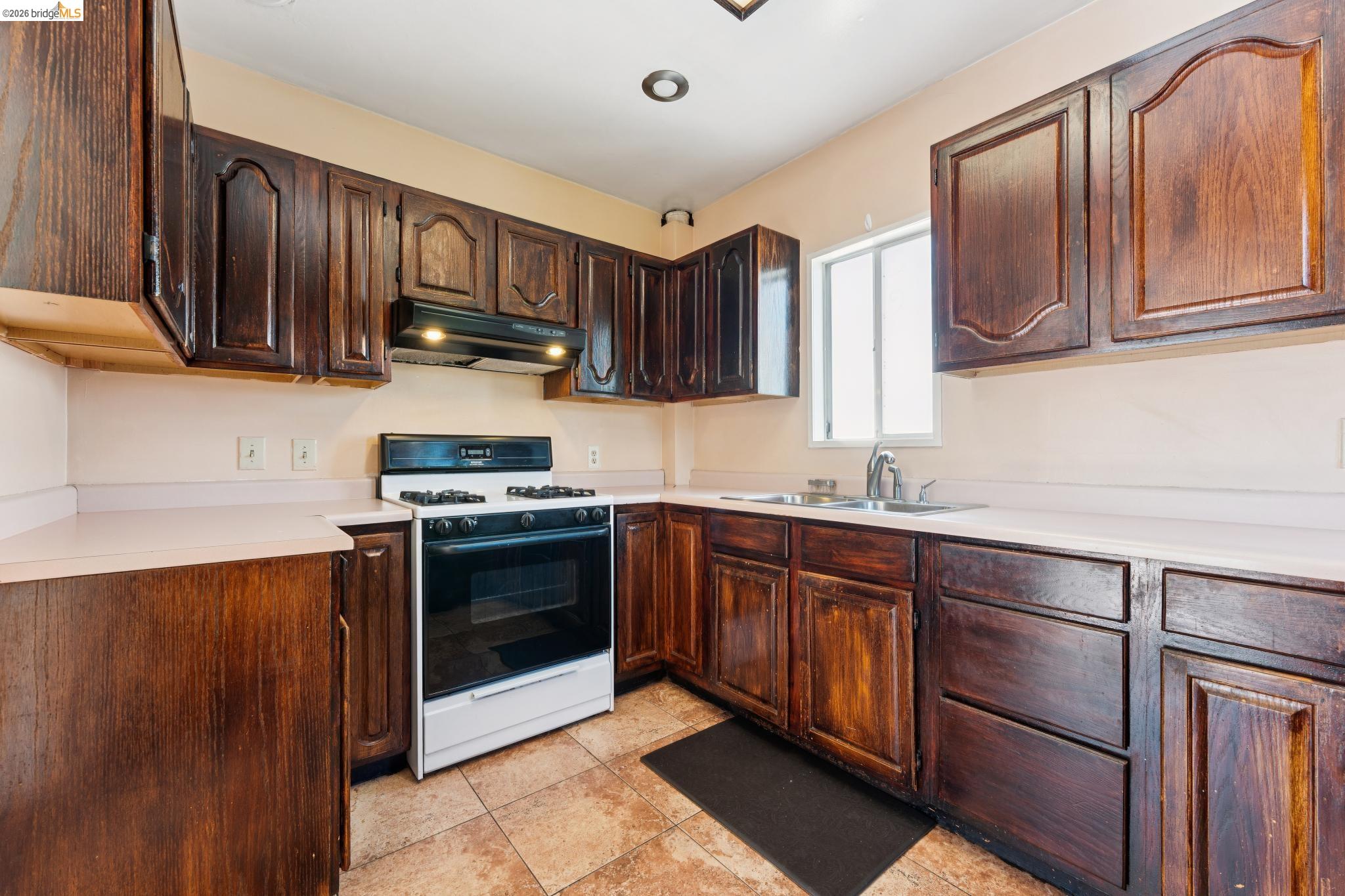 978 43rd Street Oakland, CA 94608 - Photo 16 of 46 Kitchen featuring extensive wood-finish cabinetry, light-toned countertops, and tile flooring