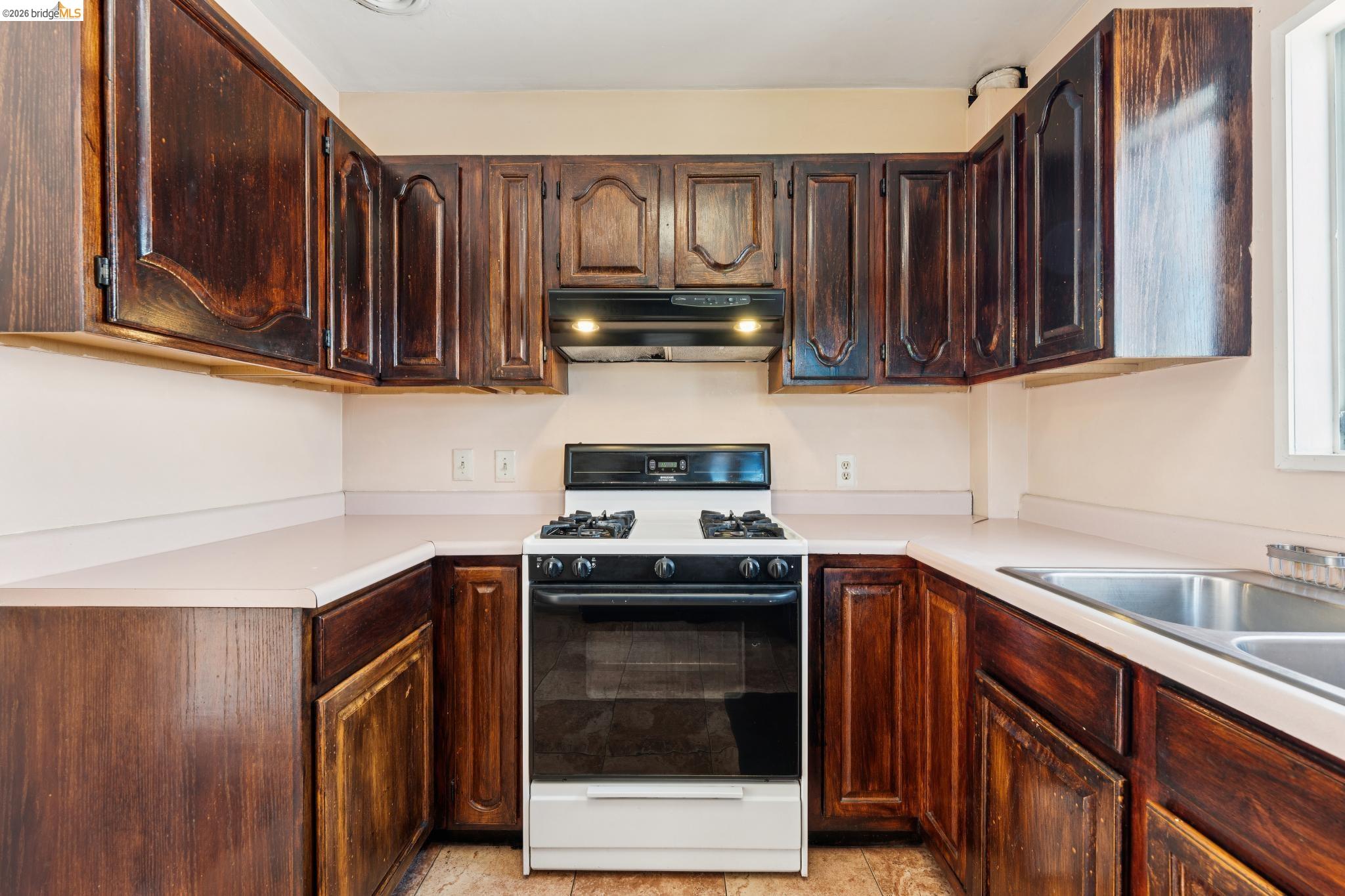 978 43rd Street Oakland, CA 94608 - Photo 17 of 46 Kitchen featuring wood-finish cabinetry, solid surface countertops, and a double basin stainless steel sink