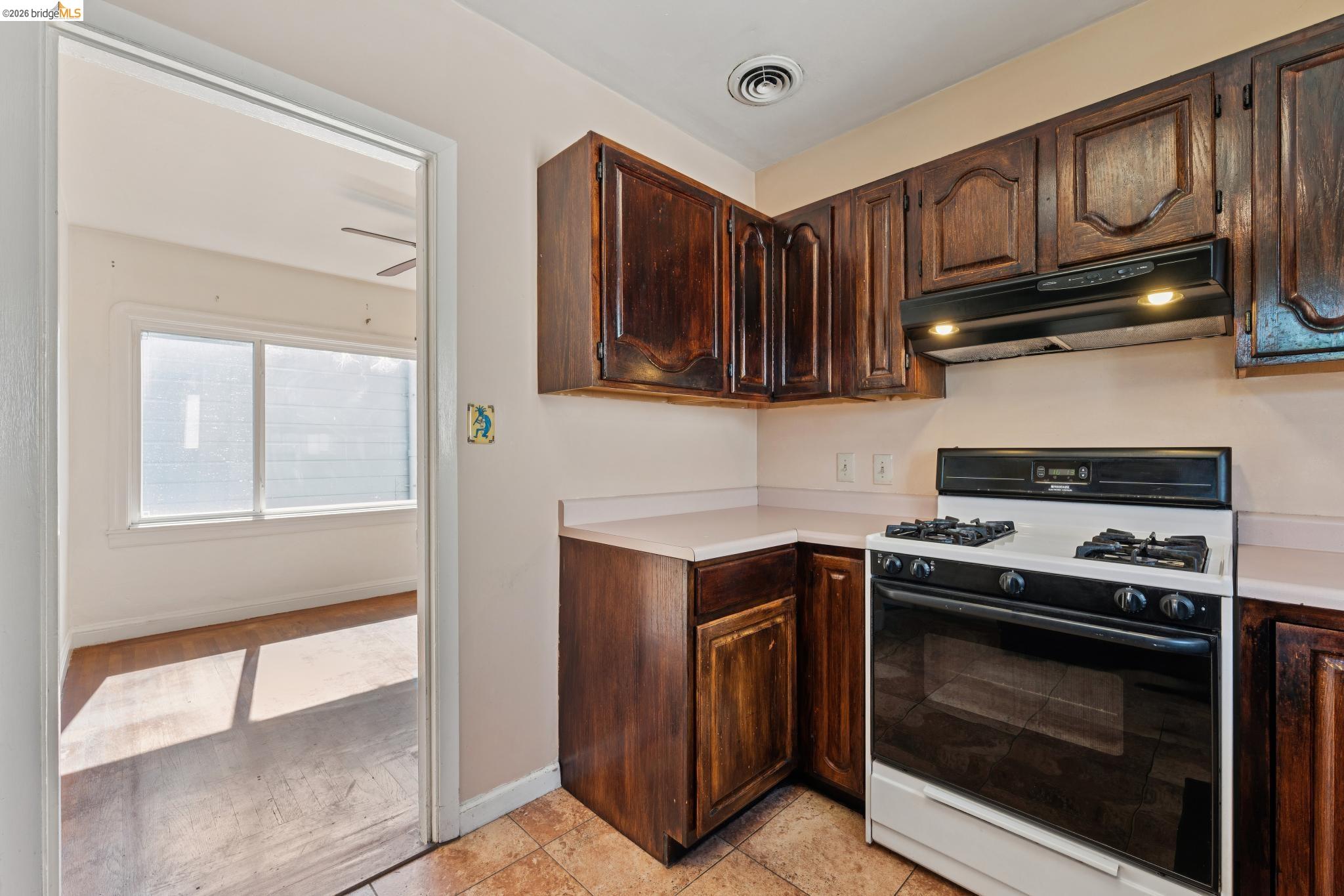 978 43rd Street Oakland, CA 94608 - Photo 18 of 46 Kitchen featuring wood cabinetry, light countertops, and a white oven/range with a black range hood