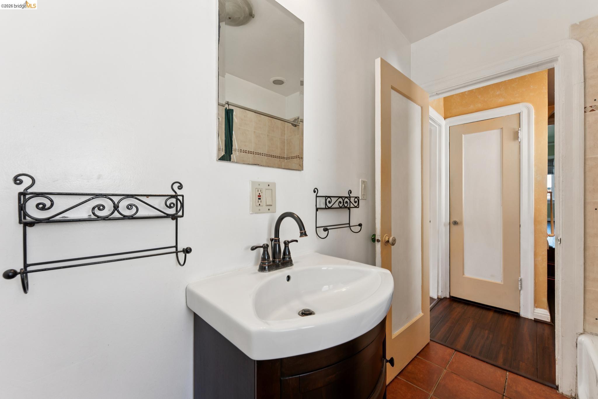 978 43rd Street Oakland, CA 94608 - Photo 22 of 46 Pedestal-style vanity with a curved front and integrated sink, bronze-finish faucet, and coordinating wall mirror