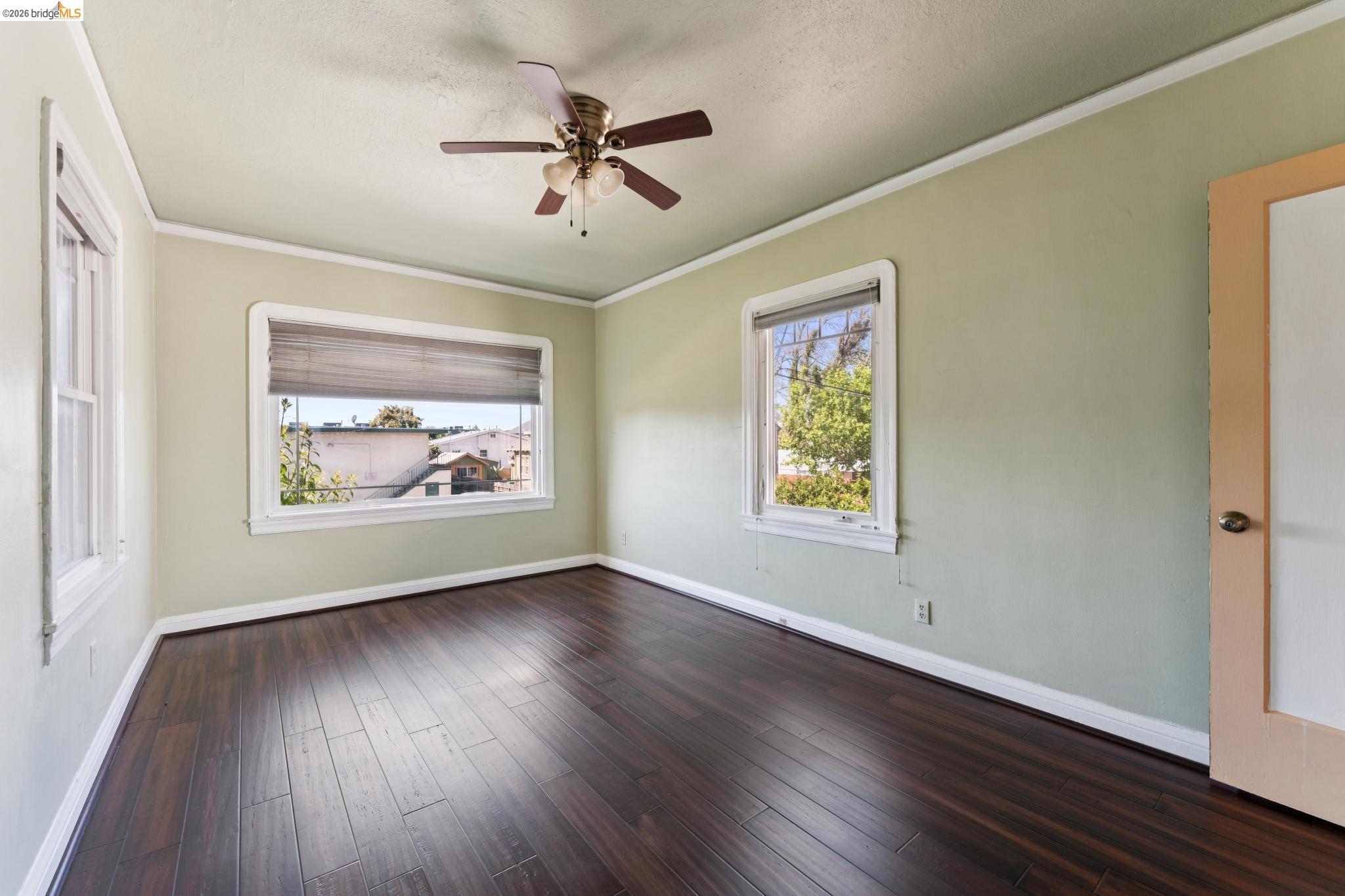 978 43rd Street Oakland, CA 94608 - Photo 26 of 46 Spacious room featuring dark wood-finish flooring, light green walls, and white crown molding