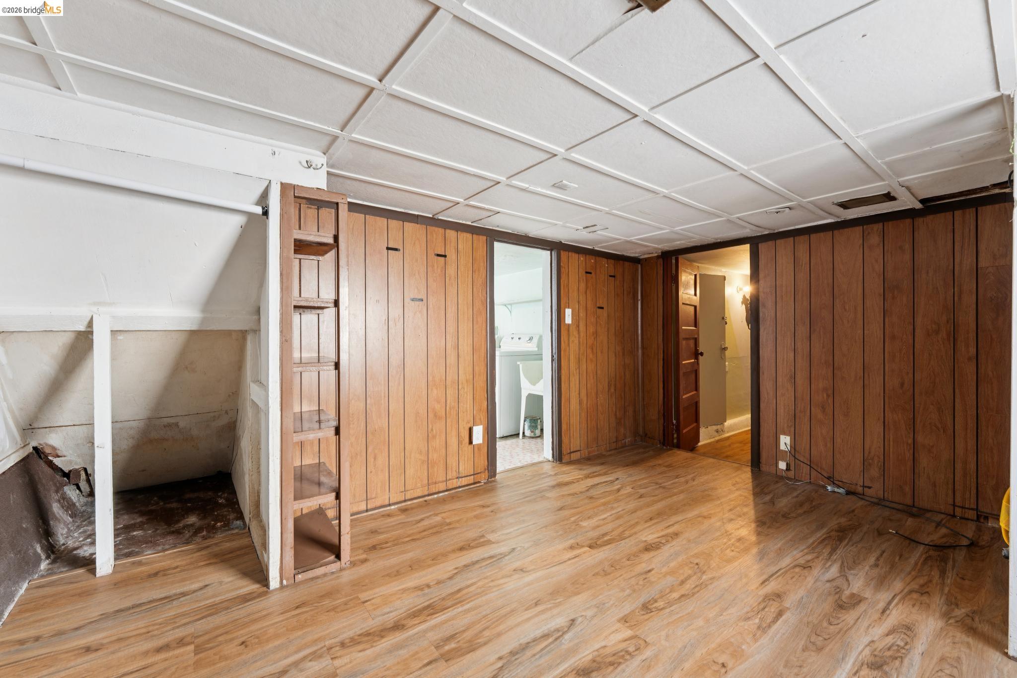 978 43rd Street Oakland, CA 94608 - Photo 31 of 46 Room featuring wood-finish flooring, wood paneling, and a white grid ceiling