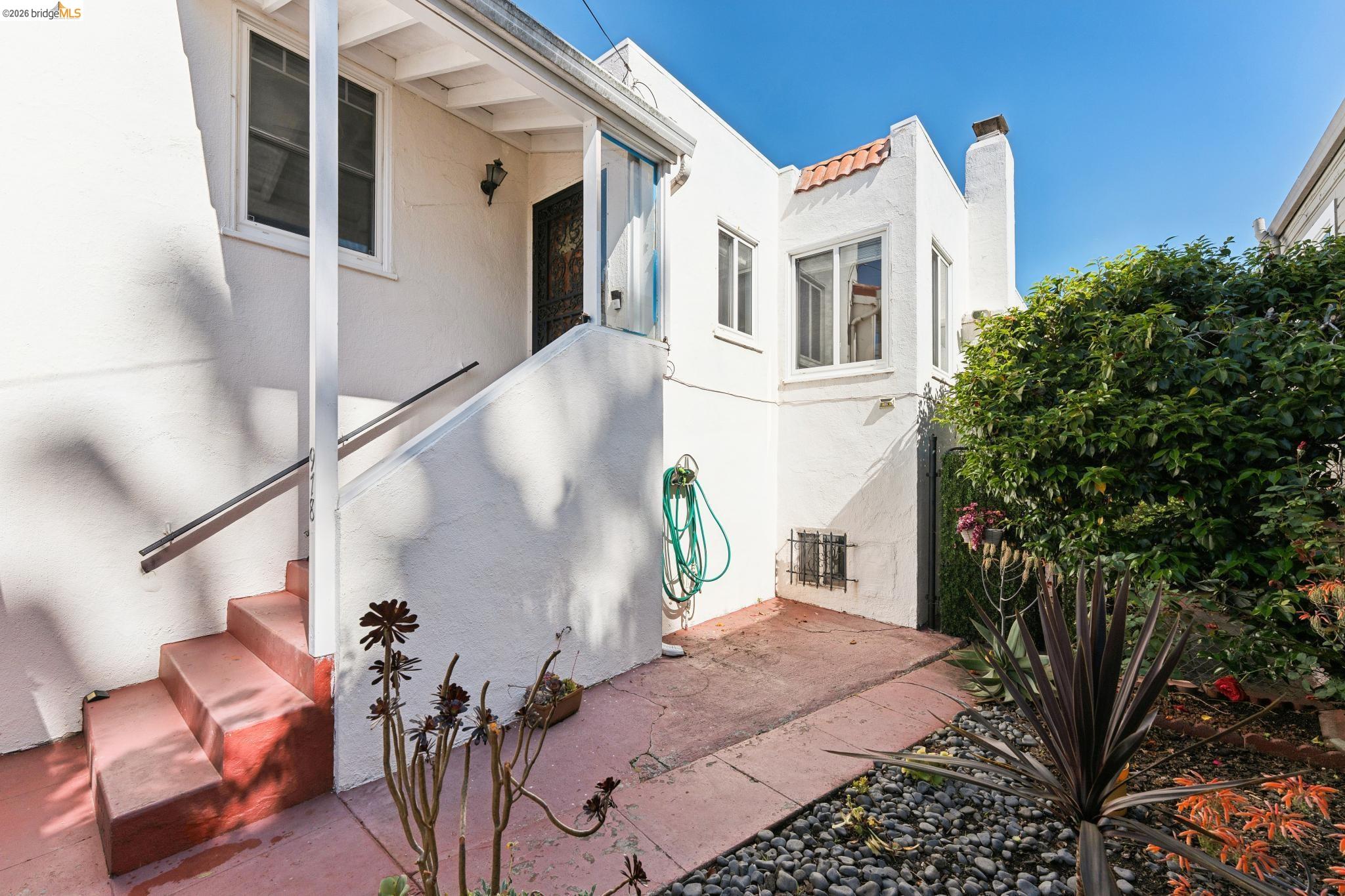 978 43rd Street Oakland, CA 94608 - Photo 5 of 46 Exterior architecture featuring white stucco, terracotta roof tiles, and an entry staircase with metal handrails