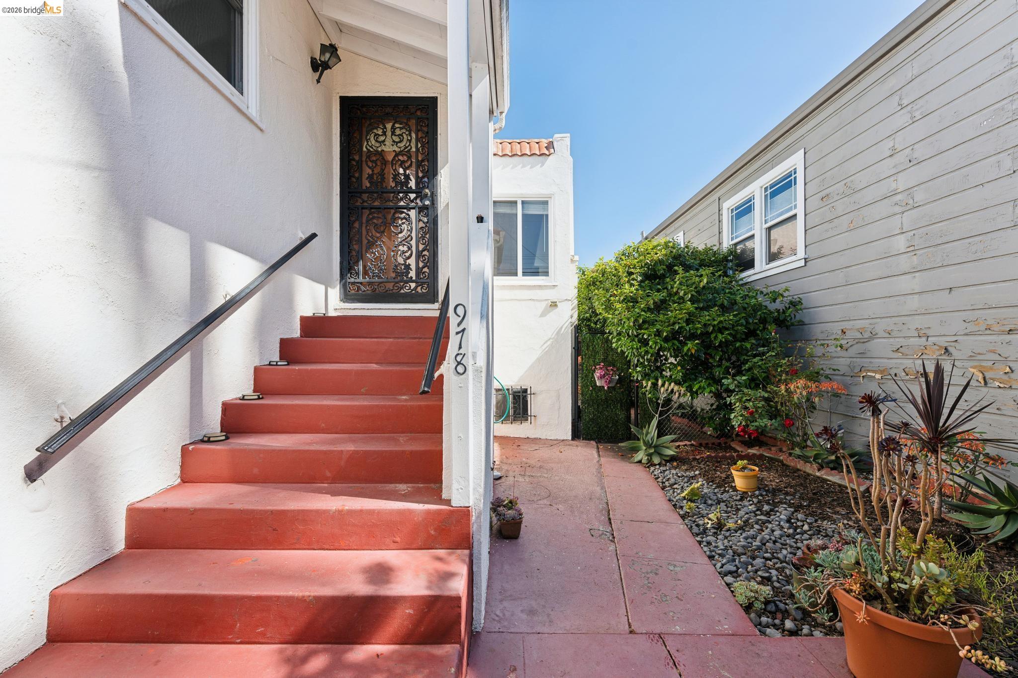 978 43rd Street Oakland, CA 94608 - Photo 6 of 46 Concrete steps with a contrasting handrail leading to a decorative iron security door