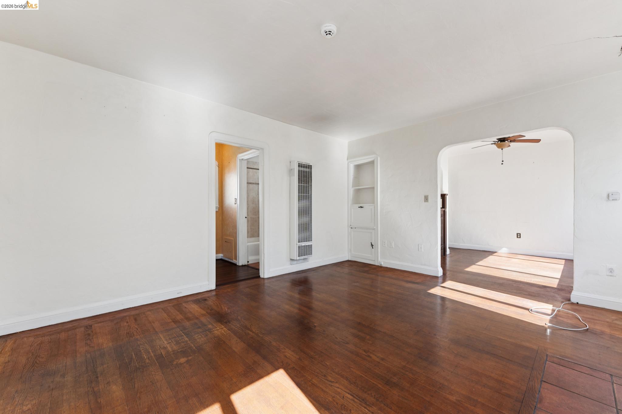 978 43rd Street Oakland, CA 94608 - Photo 8 of 46 Spacious interior featuring wood-finish flooring, white walls, built-in shelving, and an arched doorway