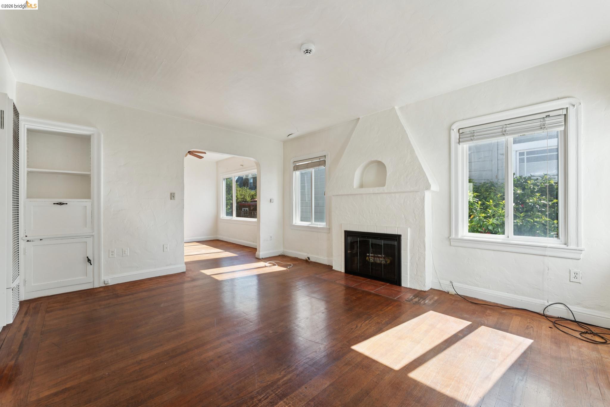 978 43rd Street Oakland, CA 94608 - Photo 9 of 46 Living area featuring rich wood-finish flooring, a painted fireplace with an arched niche, and built-in cabinetry with shelving