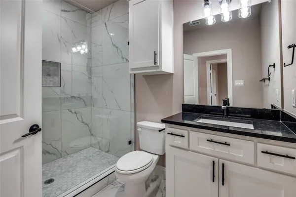 a bathroom with a granite countertop sink a toilet a mirror and shower
