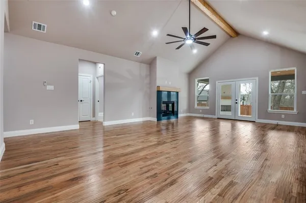 an empty room with wooden floor and windows