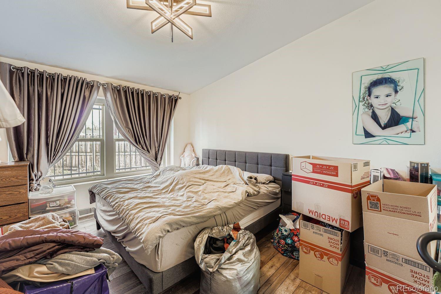 7393 Raleigh Street Westminster, CO 80030 - Photo 13 of 22 a bedroom with a bed and a chandelier