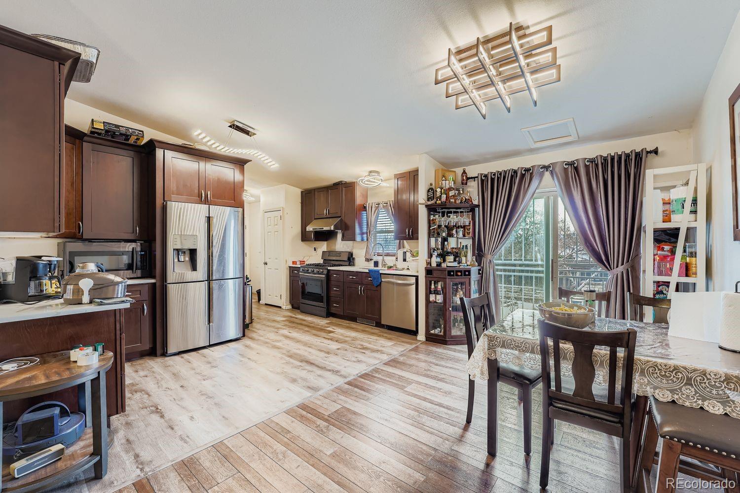 7393 Raleigh Street Westminster, CO 80030 - Photo 8 of 22 a kitchen with stainless steel appliances a refrigerator a stove a sink dishwasher a dining table and chairs with wooden floor