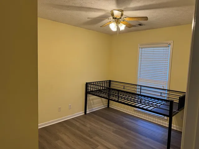 a view of a room with wooden floor and a ceiling fan