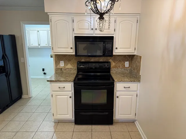 a kitchen with granite countertop white cabinets and stainless steel appliances