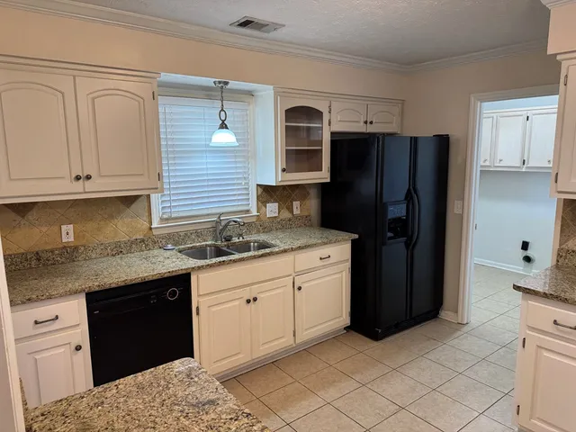 a kitchen with granite countertop a refrigerator and a sink