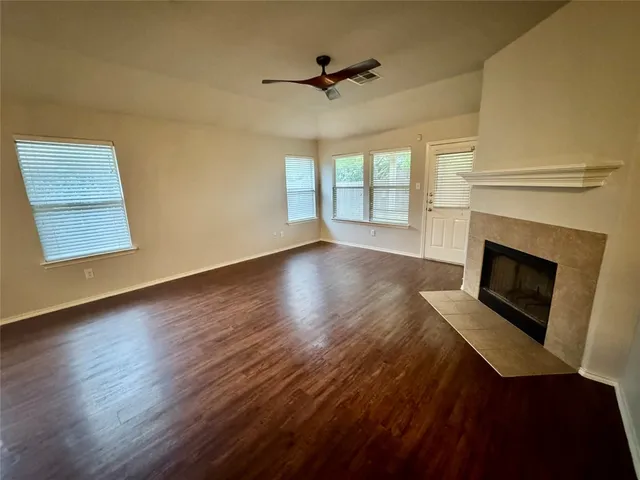 a view of an empty room with wooden floor fireplace and a window