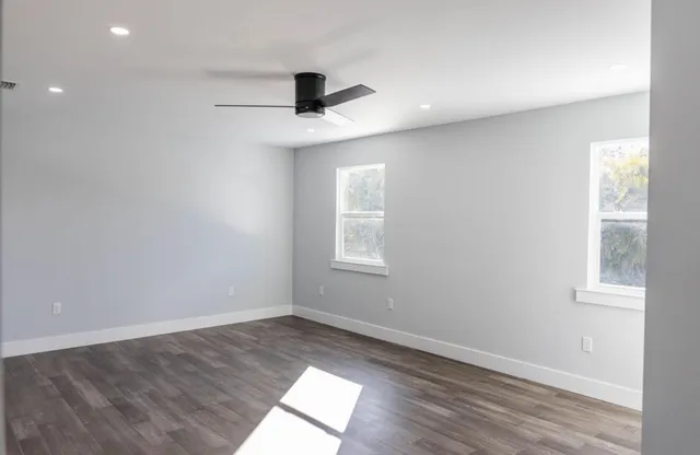 an empty room with wooden floor and windows