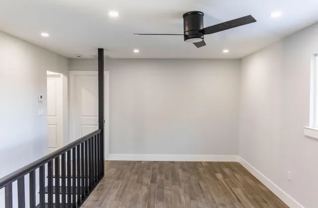 a view of a hallway with a ceiling fan and wooden floor