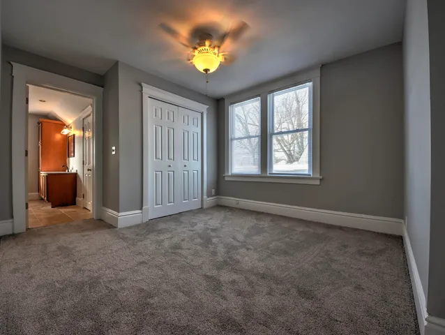 an empty room with windows and a chandelier fan
