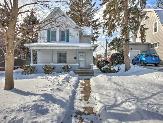 a front view of a house with a yard covered in snow