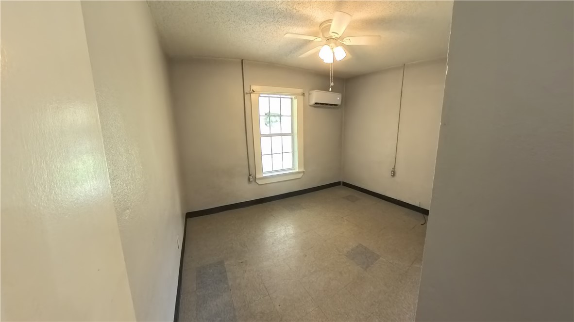 219 South 7th Street, Unit B Aransas Pass, TX 78336 - Photo 8 of 9 an empty room with a chandelier fan and windows