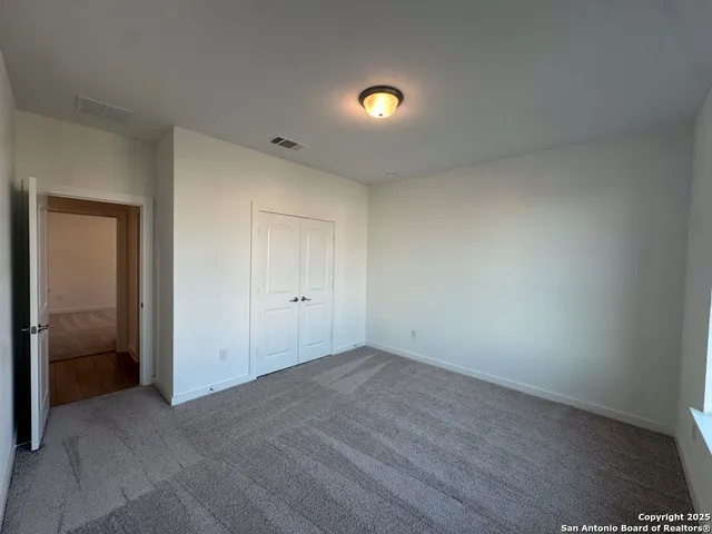 a view of an empty room with window and hardwood floor