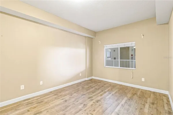 a view of empty room with wooden floor and fan