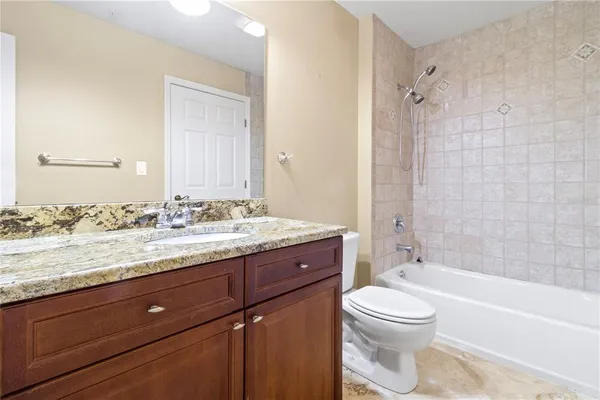 a bathroom with a granite countertop toilet a sink and a bathtub