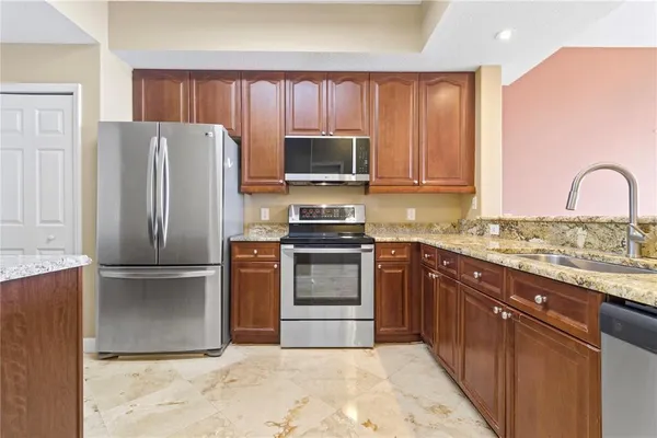 a kitchen with kitchen island granite countertop a refrigerator stove top oven and sink